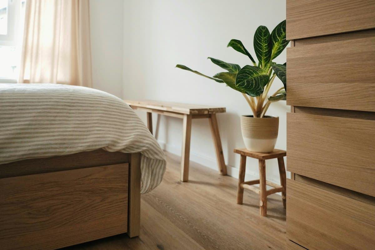 Potted plant on a wooden stool in a warm, minimal bedroom